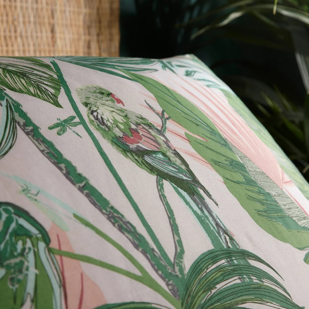 Close-up detail of the blush side of the reversible print showing a green parakeet with a red beak perched among palm fronds, banana leaves and a dragonfly – Kumperi