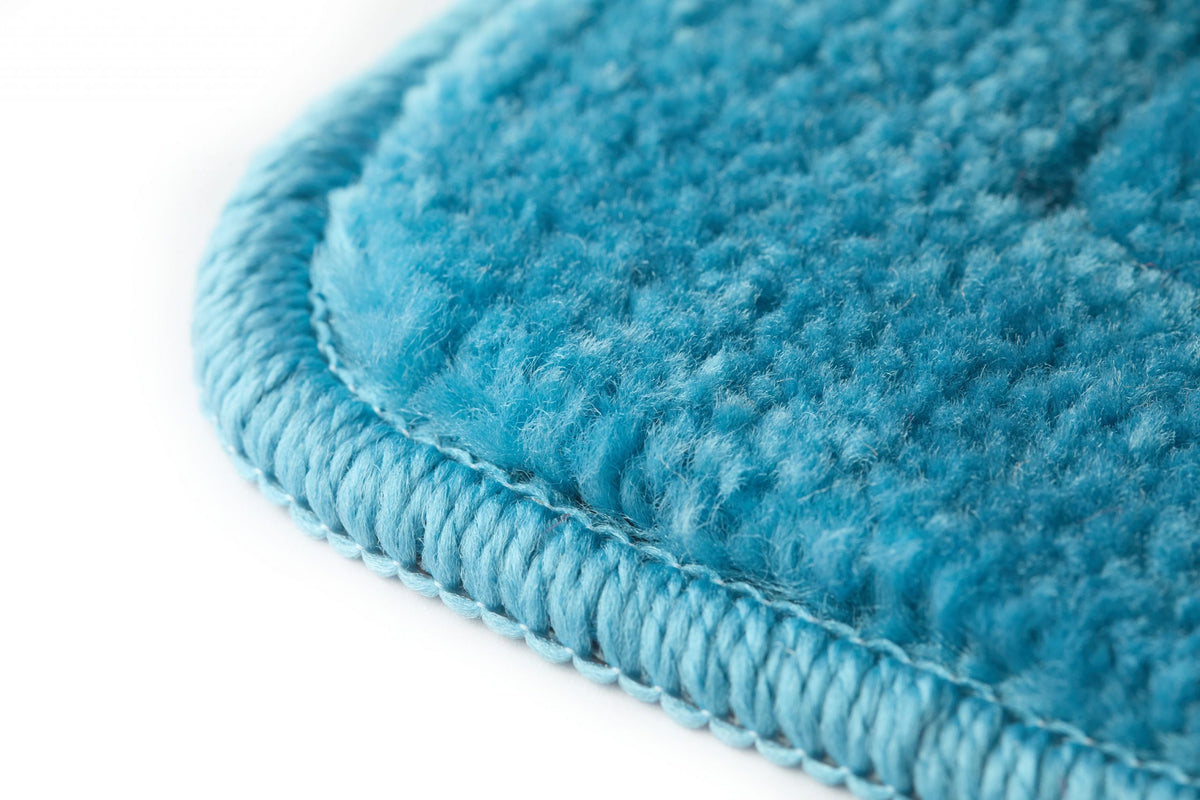 Extreme angled macro close-up of aqua polypropylene non-slip bath mat corner showing dense plush pile surface with subtle woven check relief pattern and neatly overcast-stitched edge binding in matching aqua thick soft fibre texture with tonal depth throughout Emma Barclay Lifestyle Collection Orkney