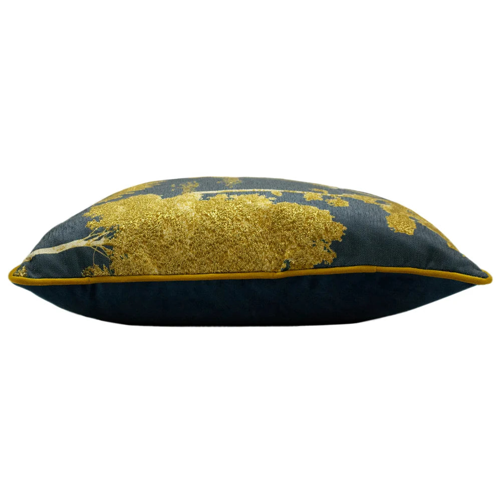 Side profile of the plump cushion showing the gold tree printed front meeting the plain petrol blue velvet reverse, edged with mustard piping – Kumperi