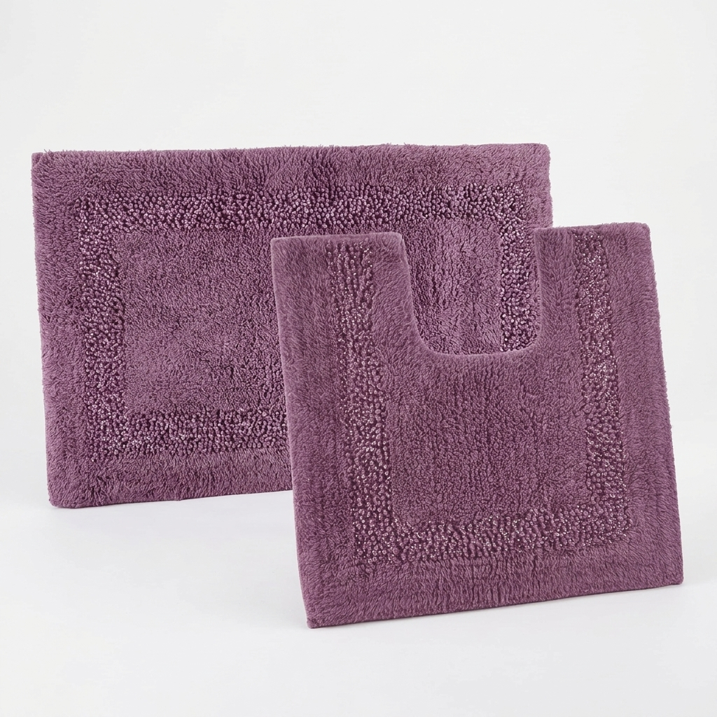 Aubergine Brillare cotton bath mat and pedestal mat overlapping on a white studio background from an alternate angle highlighting raised bobble pile and silver sparkle border trim Emma Barclay Panache Home