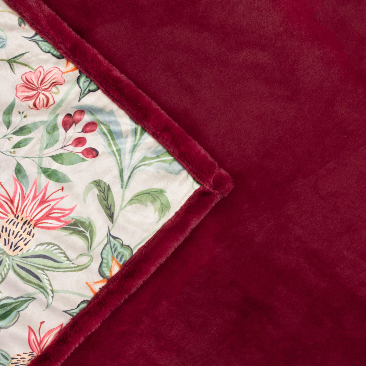 Close-up corner detail showing the cream floral velvet face with pink blooms and green leaves meeting the plush burgundy faux fur reverse and border – Kumperi