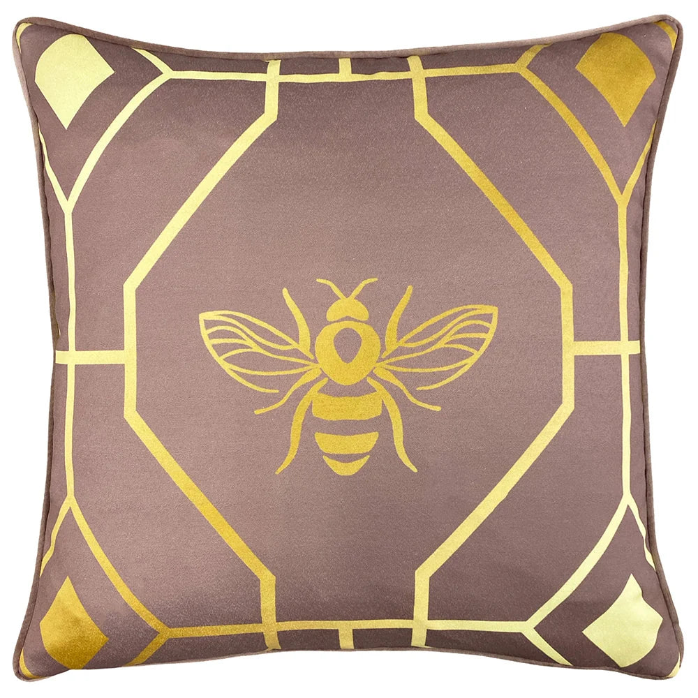 Square blush velvet cushion printed with a gold geometric octagon and diamond pattern framing a central gold outlined bee motif, edged with blush piping – Kumperi
