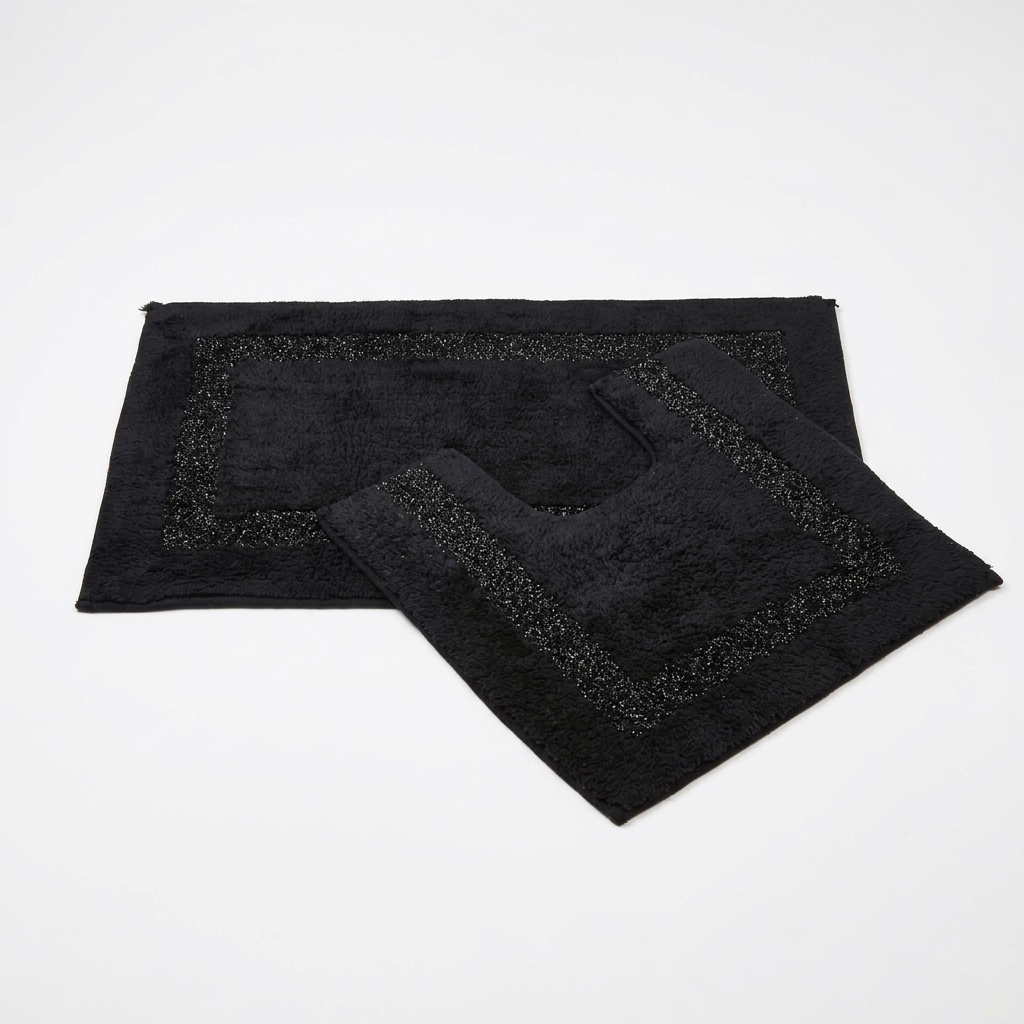 Black Brillare cotton bath mat and pedestal mat overlapping on a white studio background from an alternate angle highlighting raised bobble pile and silver sparkle border trim Emma Barclay Panache Home