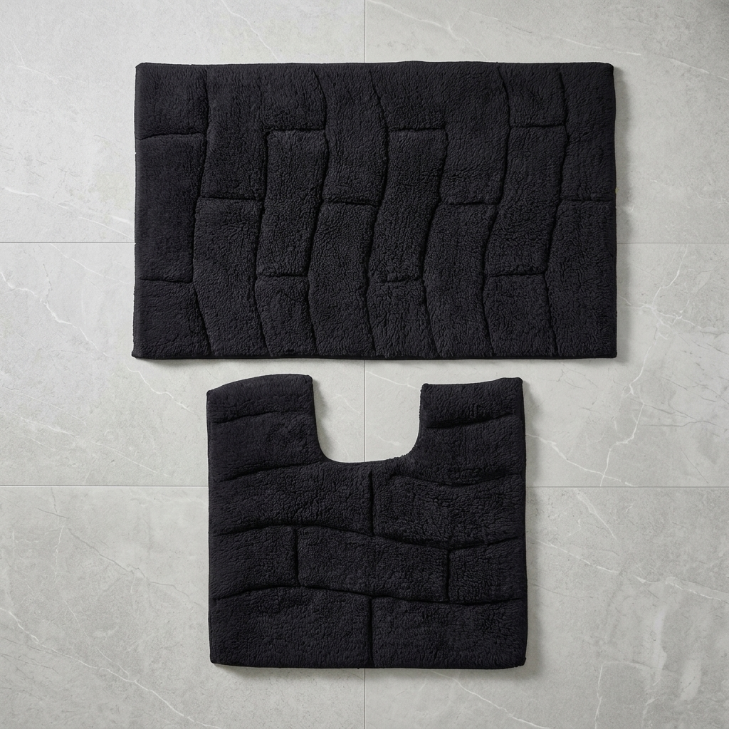 Black cotton wave block texture bath mat and pedestal mat overhead flat lay on white marble tile floor showing full mat shapes and raised wave block pile texture clearly bath mat 50x80cm pedestal mat 50x50cm 2-piece set Emma Barclay Waves design