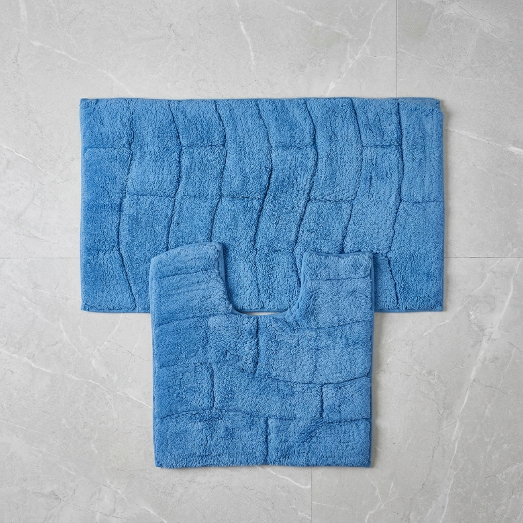 Cobalt blue cotton wave block texture bath mat and pedestal mat overhead flat lay on white marble tile floor showing both pieces with raised block pattern clearly bath mat 50x80cm pedestal mat 50x50cm 2-piece set Emma Barclay Waves design