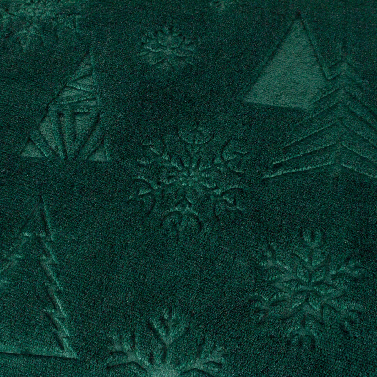 Close-up detail of the emerald fabric showing the embossed texture of triangular Christmas trees and intricate snowflake motifs – Kumperi