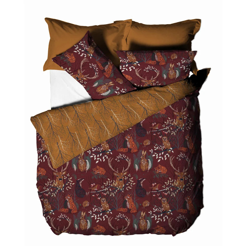 Flat top-down view of the folded duvet cover and pillowcases showing both reversible sides together, the rust woodland animal print and the mustard branch pattern – Kumperi