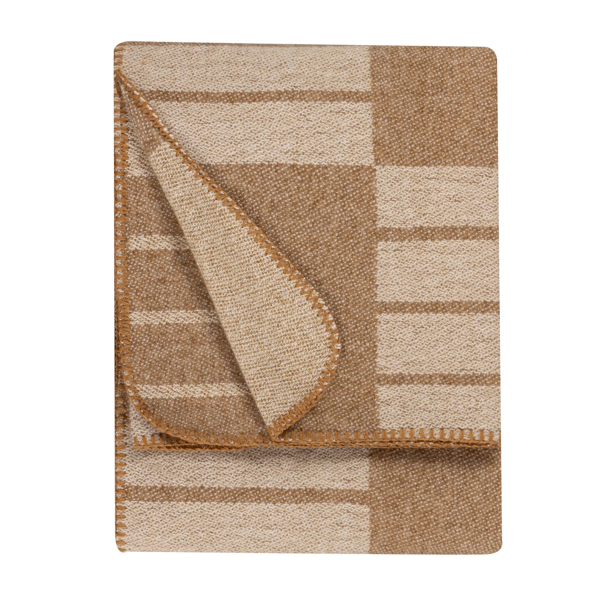 Folded biscuit and cream woven throw showing a geometric block and stripe pattern, with one corner turned back to reveal the reverse side, edged with a tan blanket stitch trim – Kumperi