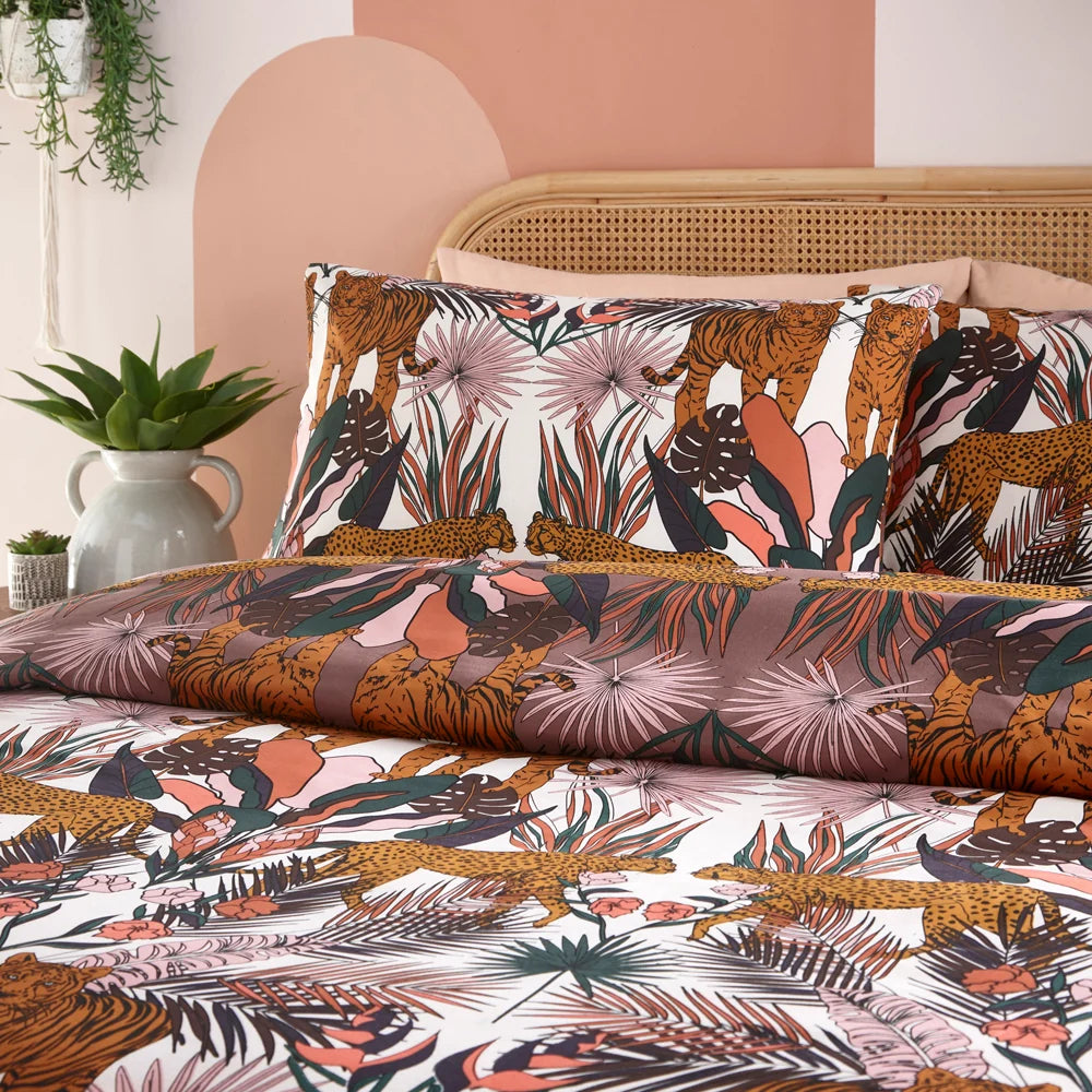 Flat close-up of the duvet cover and pillowcases showing the transition between the cocoaberry and white reversible tiger and cheetah print, with dense tropical foliage and coral floral motifs throughout – Kumperi