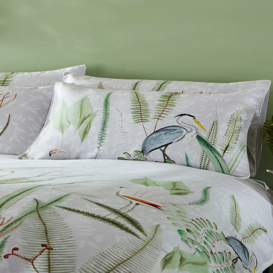 Aaliyah botanical pillowcase pair with heron and fern print on bed against sage green wall, Kumperi