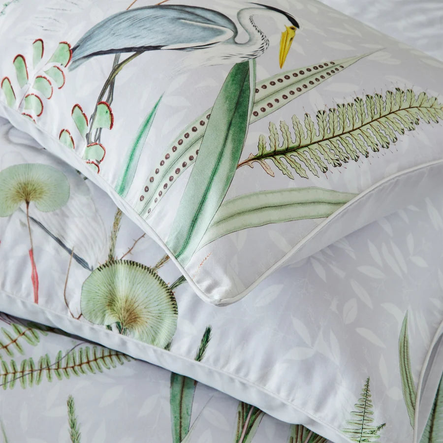 Close-up of stacked Aaliyah botanical pillowcases showing heron and botanical print with piped edge trim, Kumperi