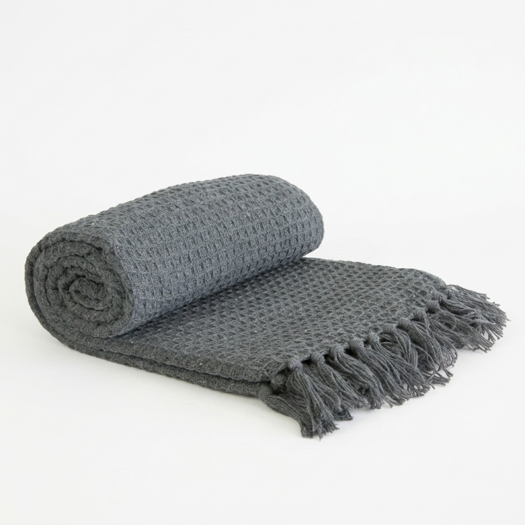 Charcoal honeycomb throw rolled up with fringe on white studio background, Kumperi