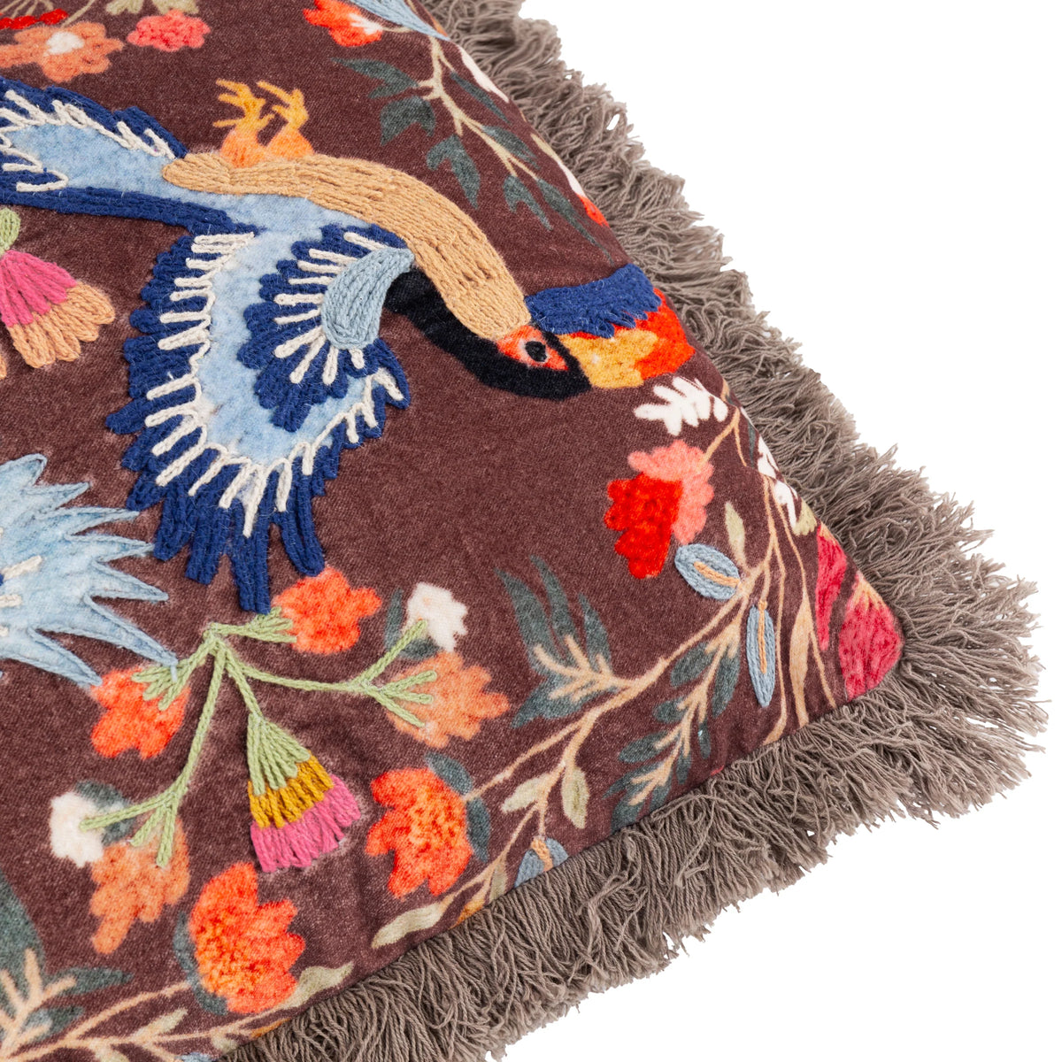 Close-up detail of the embroidery showing a navy and pale blue toucan's head with an orange and yellow beak, surrounded by tan wing feathers, pink and orange florals and green foliage on the brown ground – Kumperi
