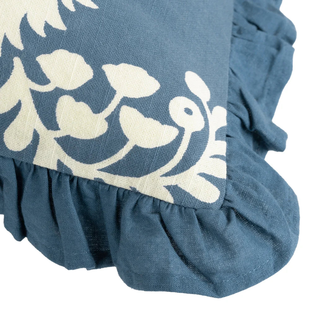 Close-up corner detail of the cushion showing the cream fern frond and floral print meeting the gathered French blue fringe trim – Kumperi