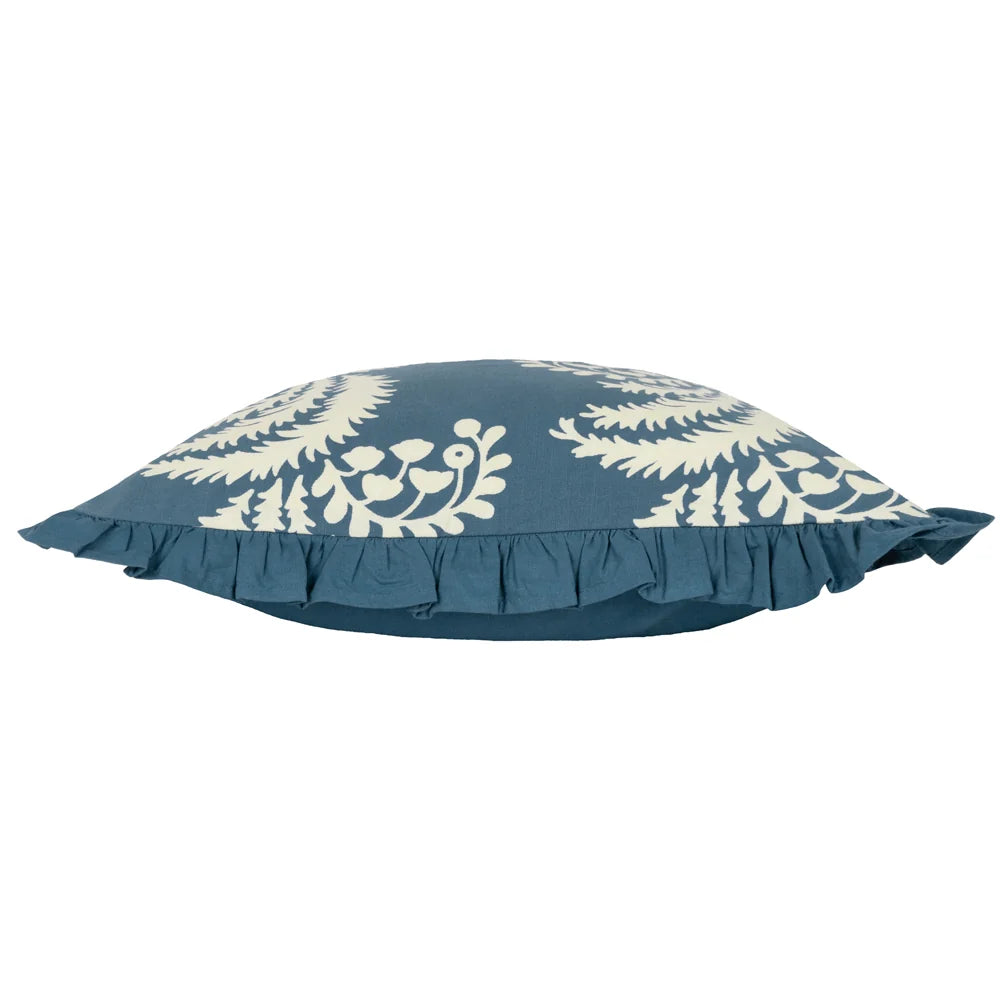 Side profile of the cushion showing the printed cream fern and floral front meeting the plain blue reverse, with the gathered fringe trim visible along the seam – Kumperi