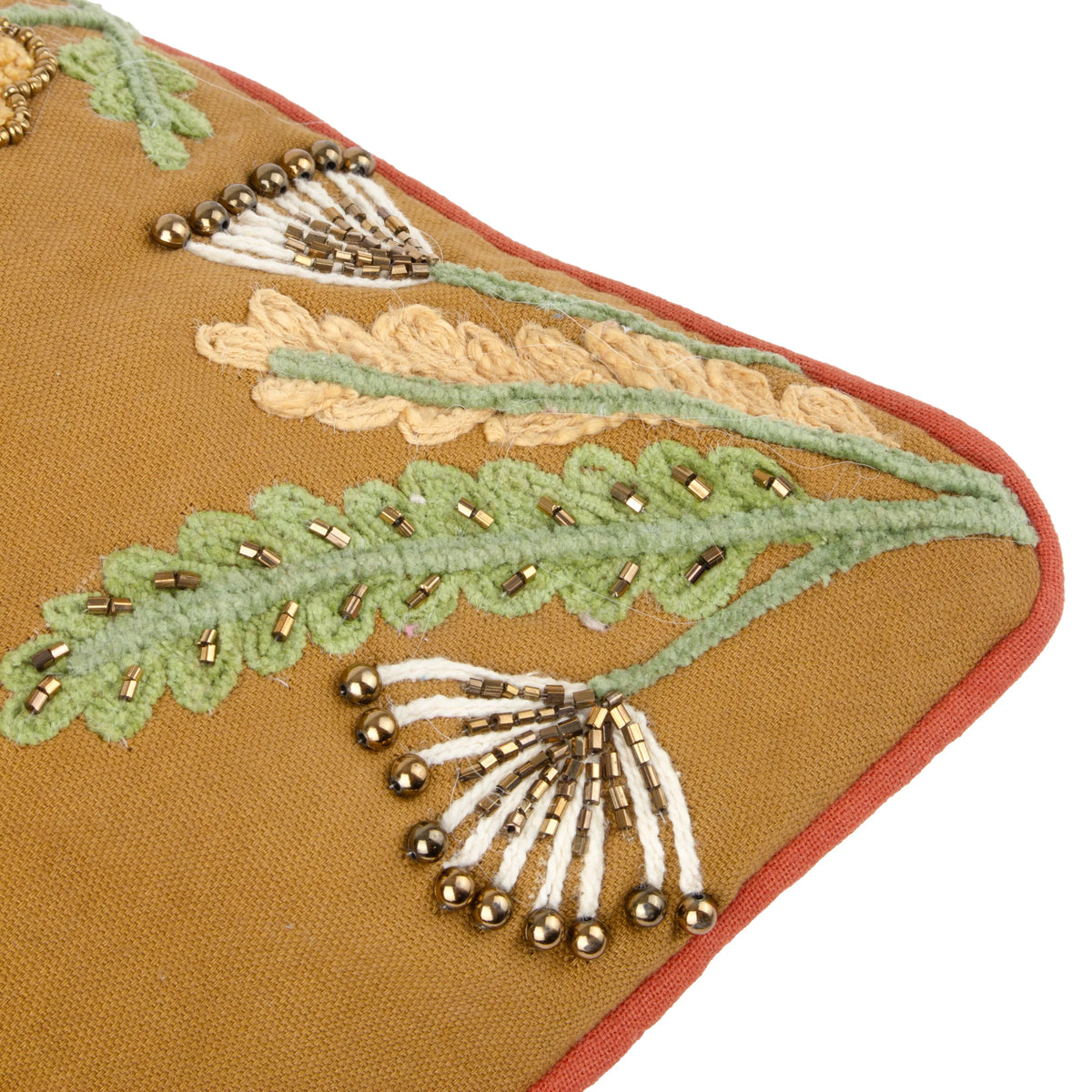 Close-up corner detail showing gold beaded dandelion seed heads, a cream corded fern leaf with metallic beading, and a green beaded fern against the mustard gold fabric with burnt orange piping – Kumperi