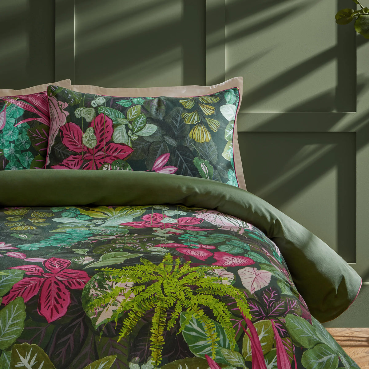 Veadeiros exotic floral pillowcase pair styled on bed with green duvet, pink/green print – Paoletti