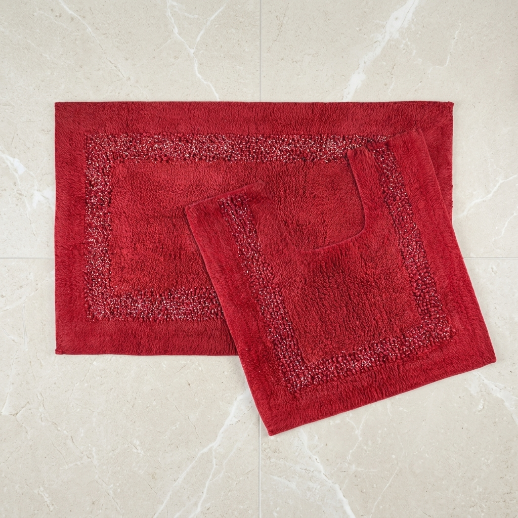 Red Brillare cotton bath mat and pedestal mat overlapping on a light tiled floor showing soft loop pile centre and metallic sparkle border trim Emma Barclay Panache Home
