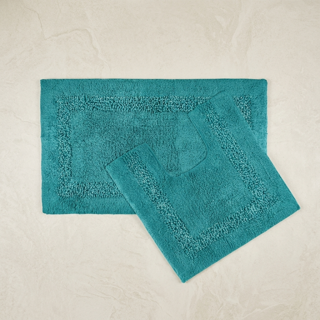 Teal Brillare 100% cotton bath mat and pedestal mat overlapping at a diagonal angle on a soft cream textured background both pieces showing the full mixed loop pile centre framed by a raised rounded bobble sparkle border trim toilet cut-out clearly visible on the square pedestal mat 2-piece set bath mat 50x80cm pedestal mat 50x50cm Emma Barclay Panache Home