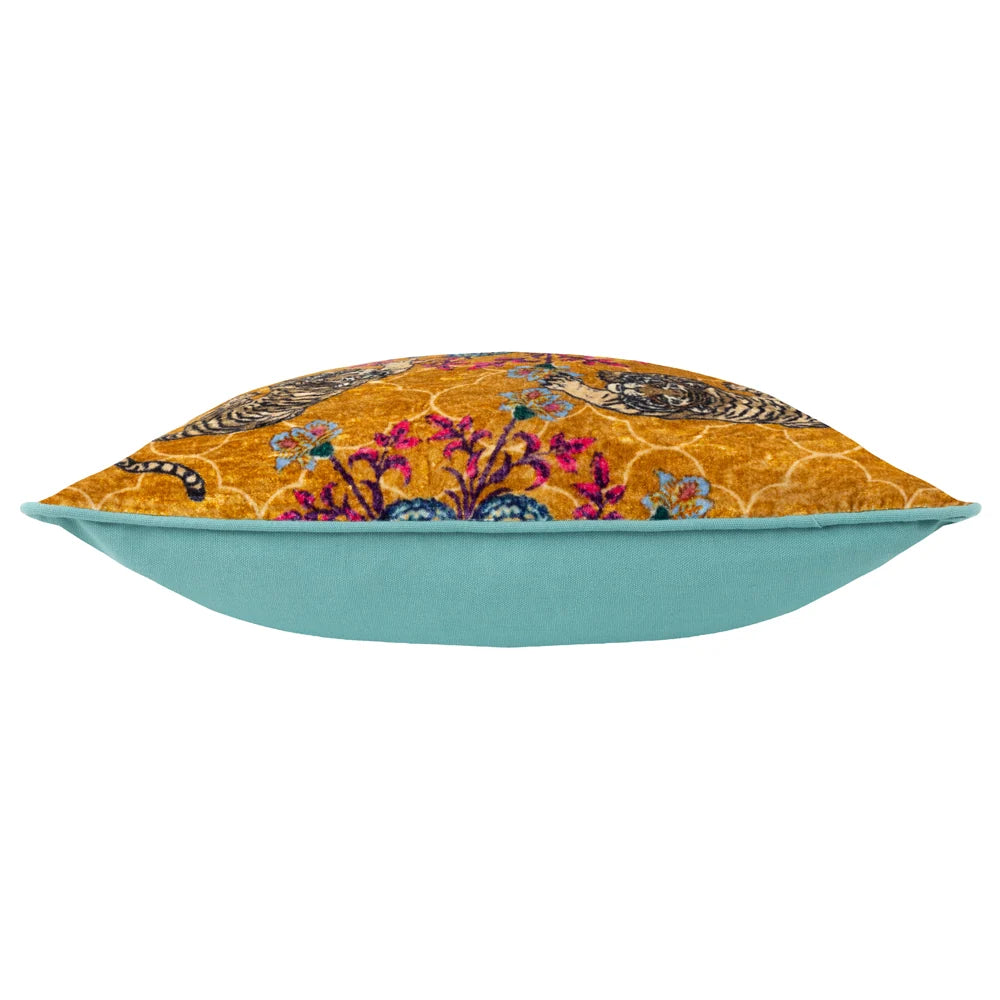 Side profile of the cushion showing the gold tiger print velvet front meeting the plain teal cotton reverse along a teal piped seam – Kumperi