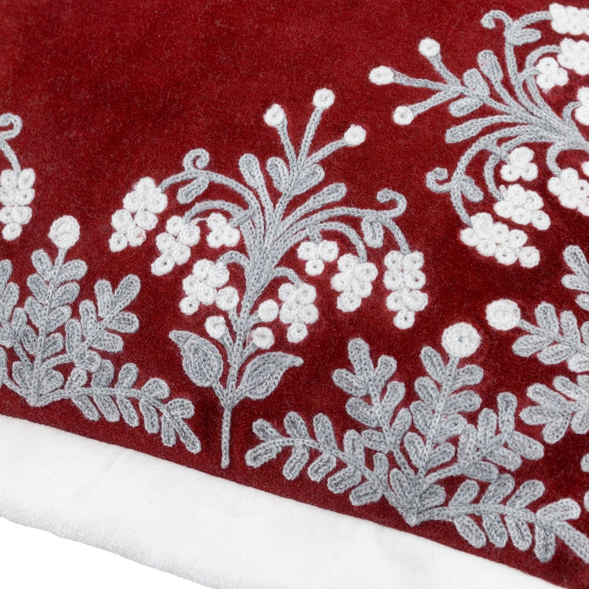Close-up detail of the embroidered border showing grey scrolling foliage and white berry clusters worked densely against the red velvet ground – Kumperi